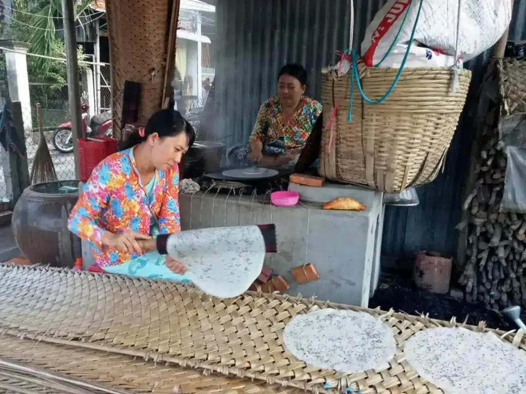 Nghệ nhân tráng bánh đang thực hiện công đoạn tráng bánh trên khuôn vải, thể hiện kỹ thuật thủ công truyền thống.